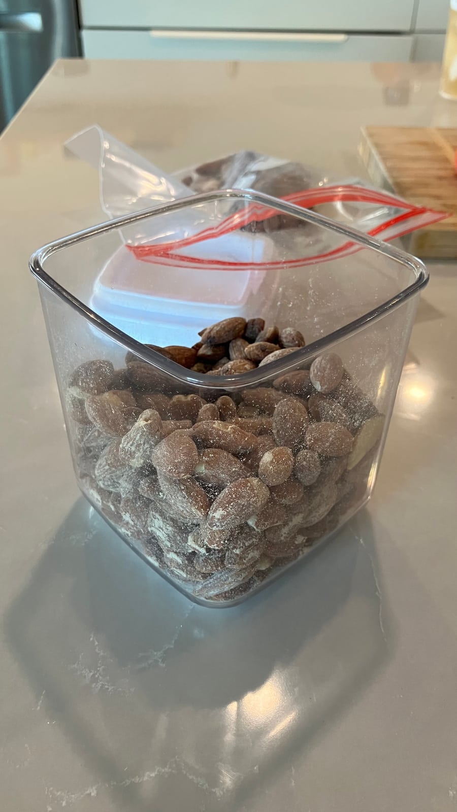 Close view of almonds in the container with pale powdery residue on their surfaces and the walls